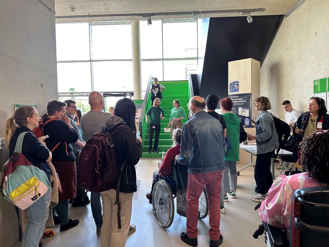 Bildbeschreibung: Das Foto zeigt unterschiedliche Personen, die am Disability Pride Day an der HSD teilnehmen. In der fotografierten Szene werden von den Organisator*innen Informationen an die Teilnehmer*innen kommuniziert (Foto: Janieta Bartz).